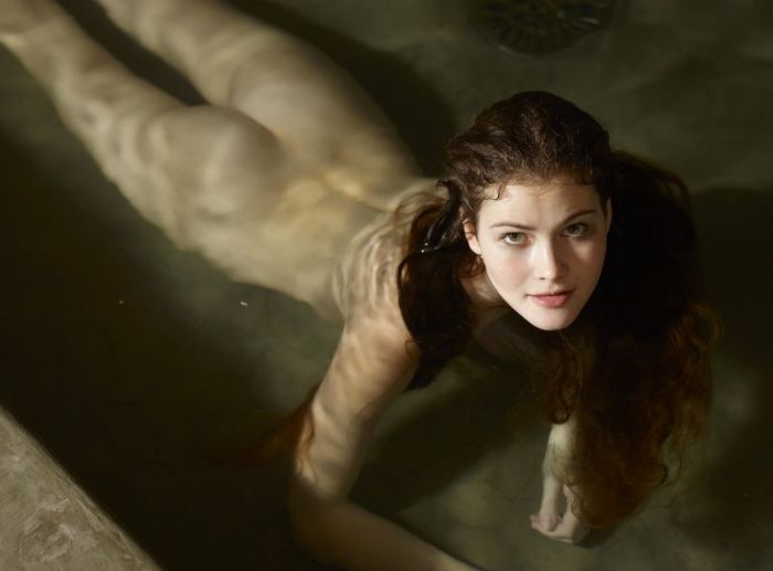 Мокрая девушка голышом в бассейне